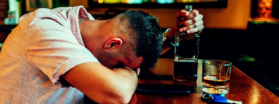 Young caucasian drunk man sleeping on bar counter