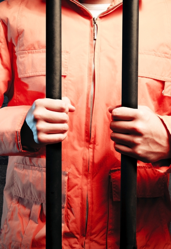 inmate wearing orange overalls inside a prison cell