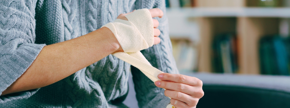 Injured woman hands removing bandage from arm