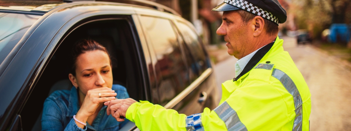 Man and woman, police officer making a traffic stop on the street, alcohol test in motion.