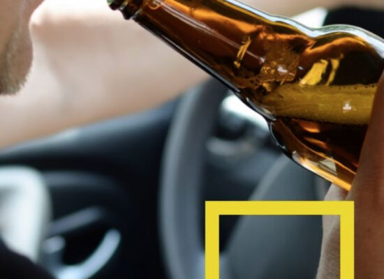 DUI attorney in Bloomington IL portrayed Person drinking from a beer bottle in a car.