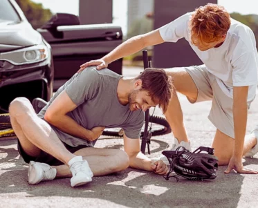 Young man hurt on a bike crash after hit by a car while another young man assisting him. lying about a car accident