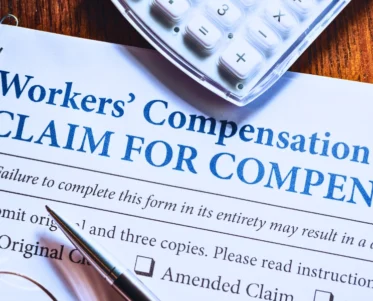 Workers' Compensation form with pen and glasses. Injured while driving for work